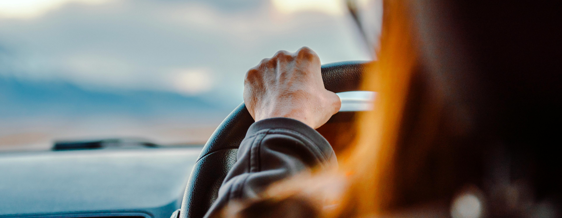 Close-up of a driving instructor’s hand on the steering wheel during a lesson