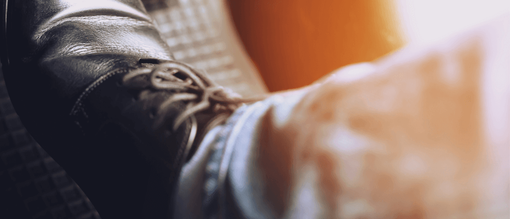 Close up of a driver’s foot pressing a car pedal, showing a leather shoe and jeans inside a vehicle.