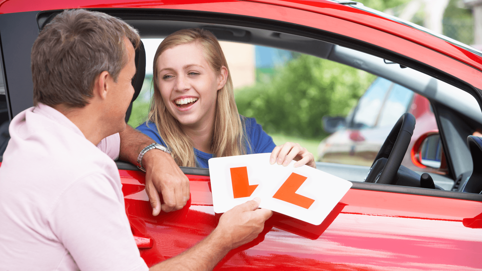 Learner driver holding L plates during lesson with instructor